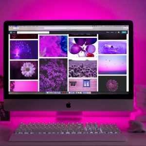 Modern desk setup with neon lighting and a desktop computer displaying colorful images.